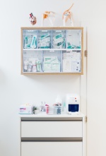 Vitrine für Verbandsmaterial aus Holz mit Glastüre.