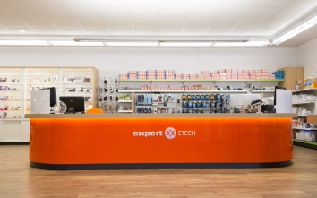 Orangenes Kassenpult mit Runden Ecken im Elektrofachhandel der Marke expert.