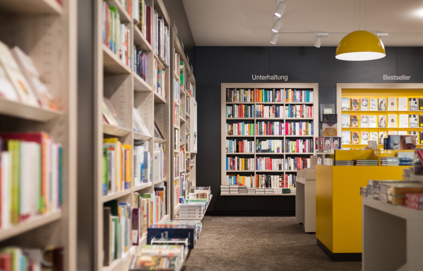 Überischt über die Buchhandlung Tyrolia mit Mittelraumgonel, Präsentationstisch und Buchpräsentation an der Wand.