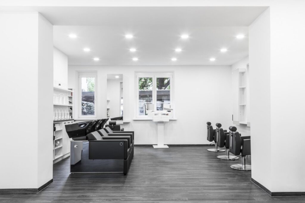 Hochwertig möblierter Friseursalon mit Bedienstühlen, Spiegeln, Waschplatz und Empfangstheke